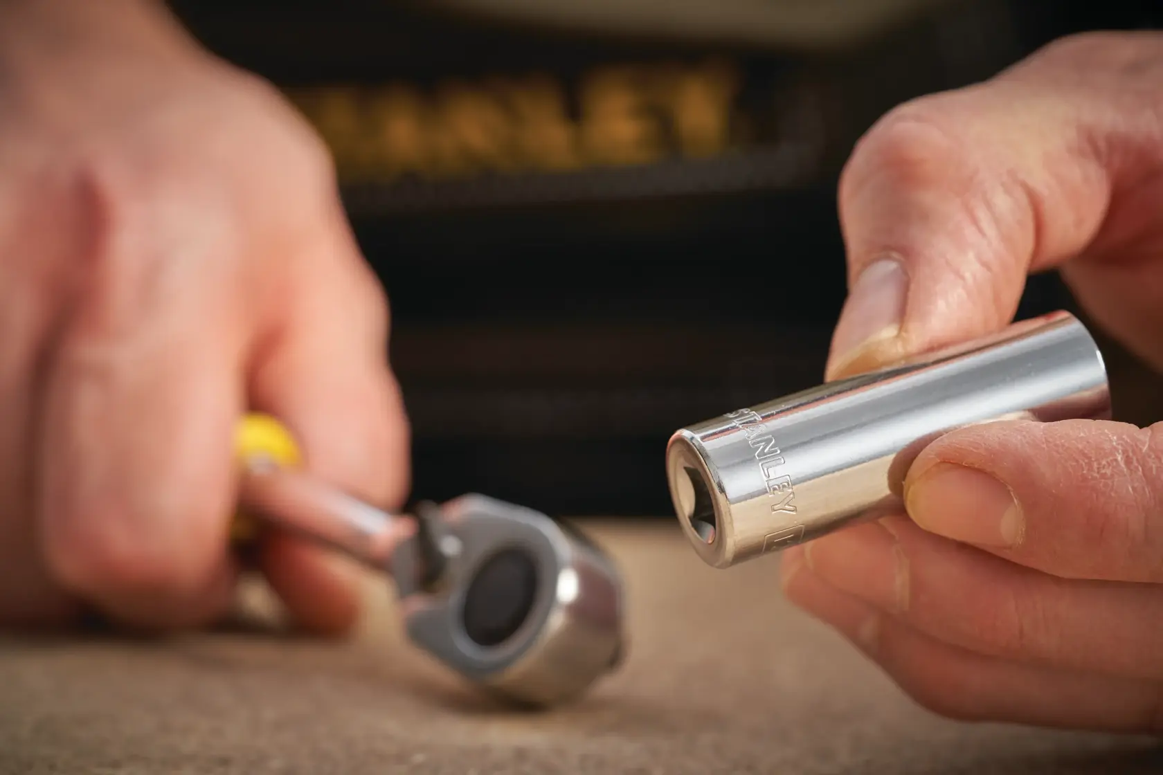 STANLEY STMT86097-0 socket held by hand with ratchet wrench on table, close-up view, tool photography.