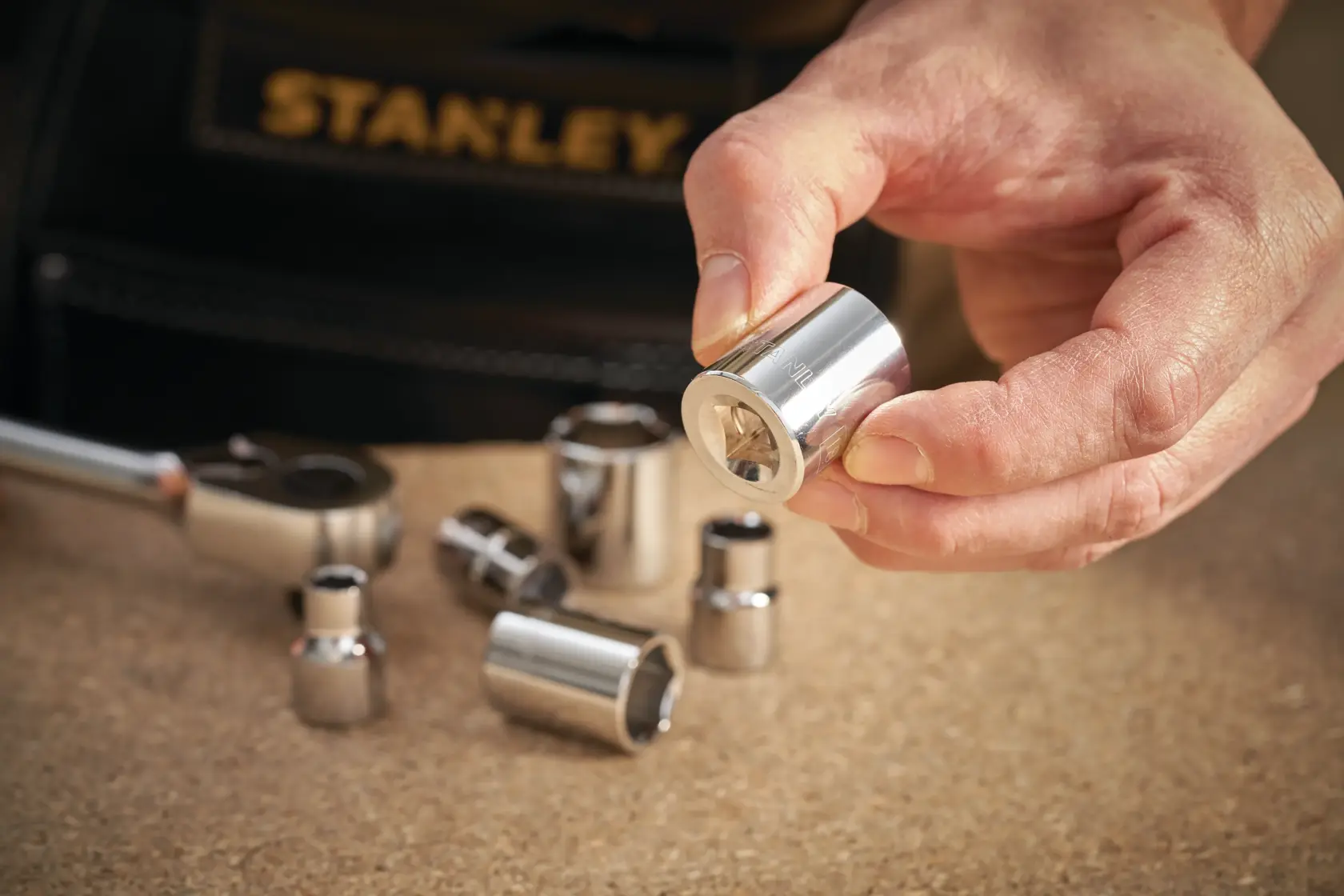 Photo of STANLEY STMT86305-0 socket set pieces on a work surface, one socket held in hand.