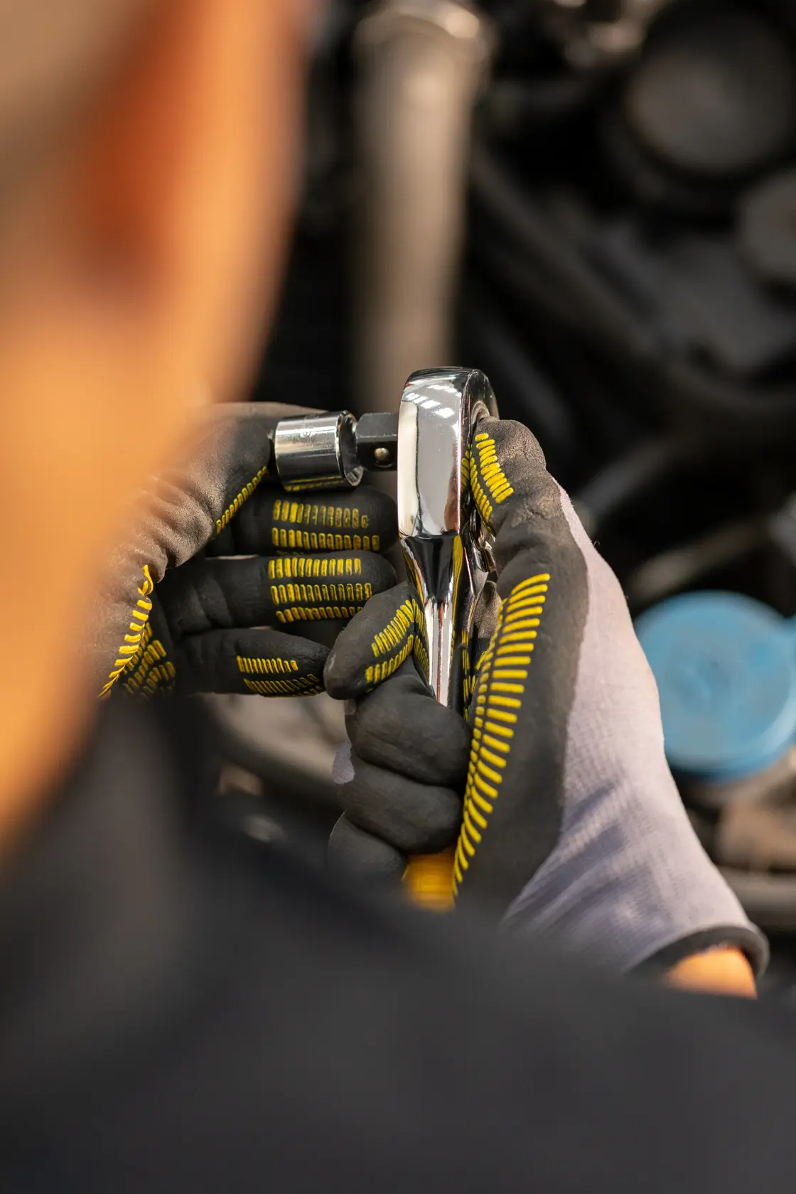 Photo of STANLEY STMT86522-0 ratchet held by gloved hands, close-up view, automotive setting.