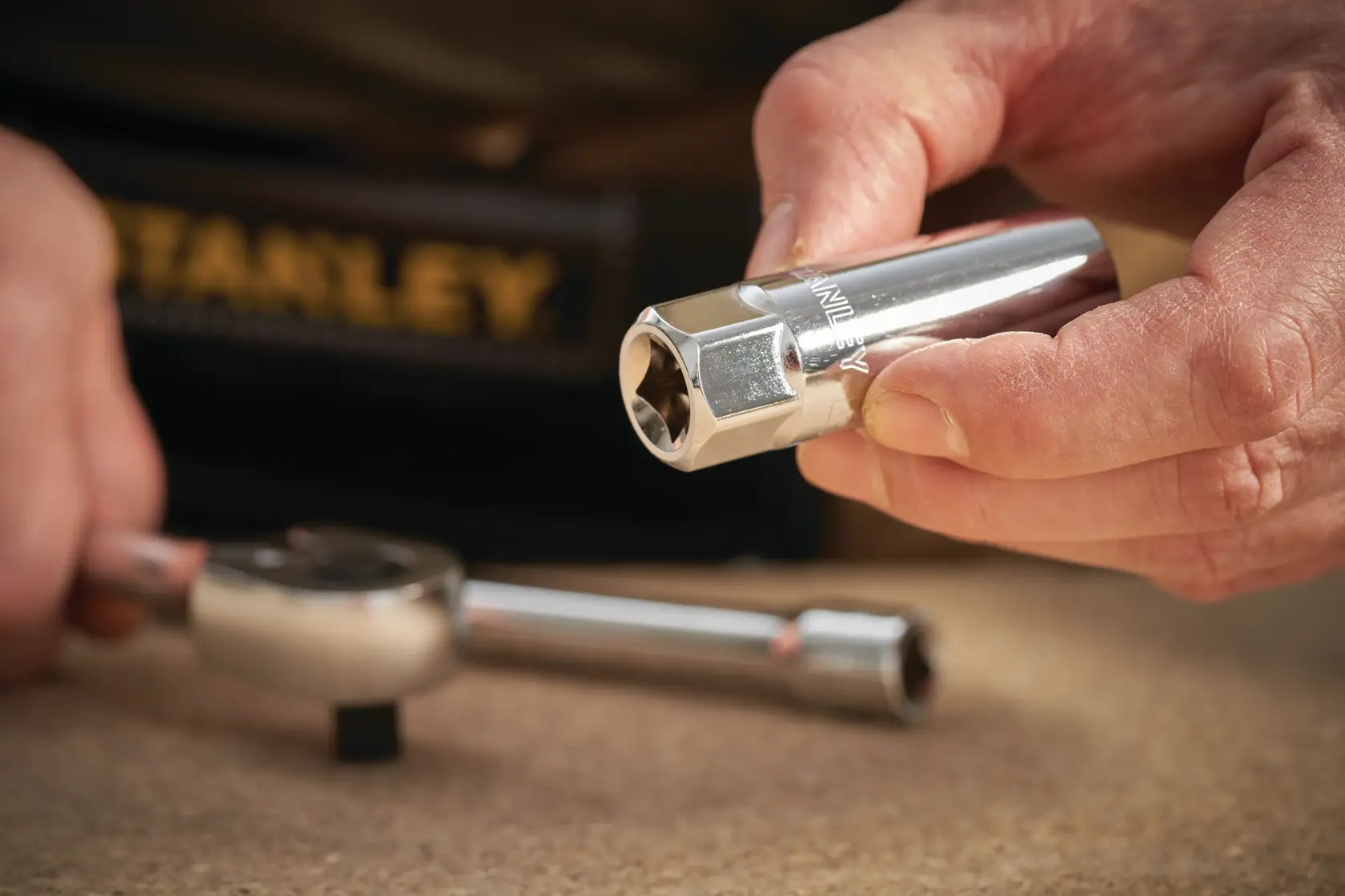 STANLEY STMT88941-0 socket held by hand, with ratchet wrench on table, close-up photography.
