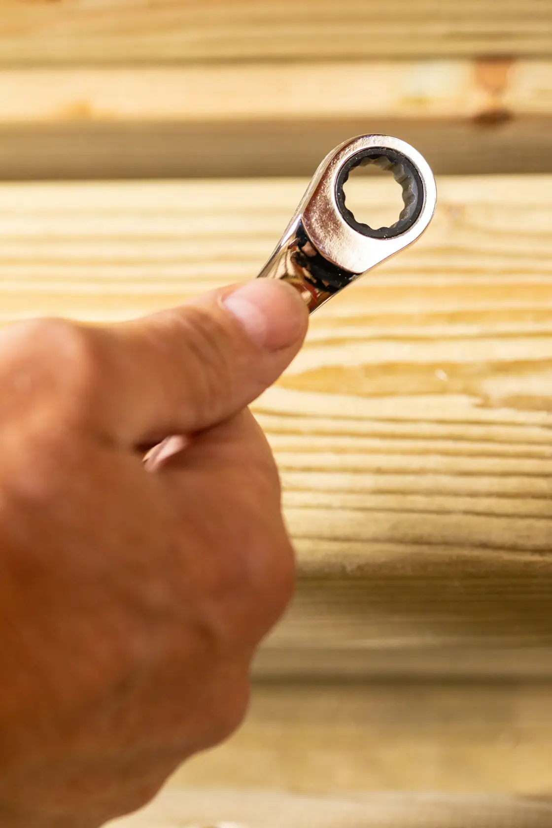 Photo of STANLEY STMT89917-0 ratcheting wrench held in hand near wood surface.