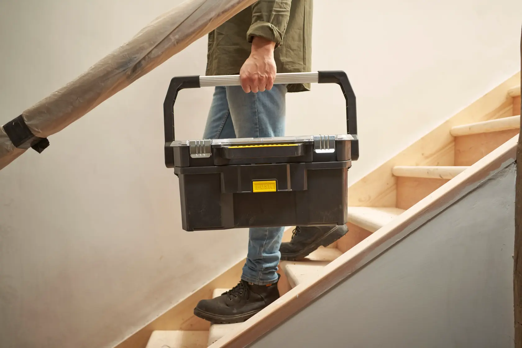 STANLEY STST1-70317 schwarze Werkzeugbox mit silbernem Griff beim Treppenaufstieg, Produktfotografie.