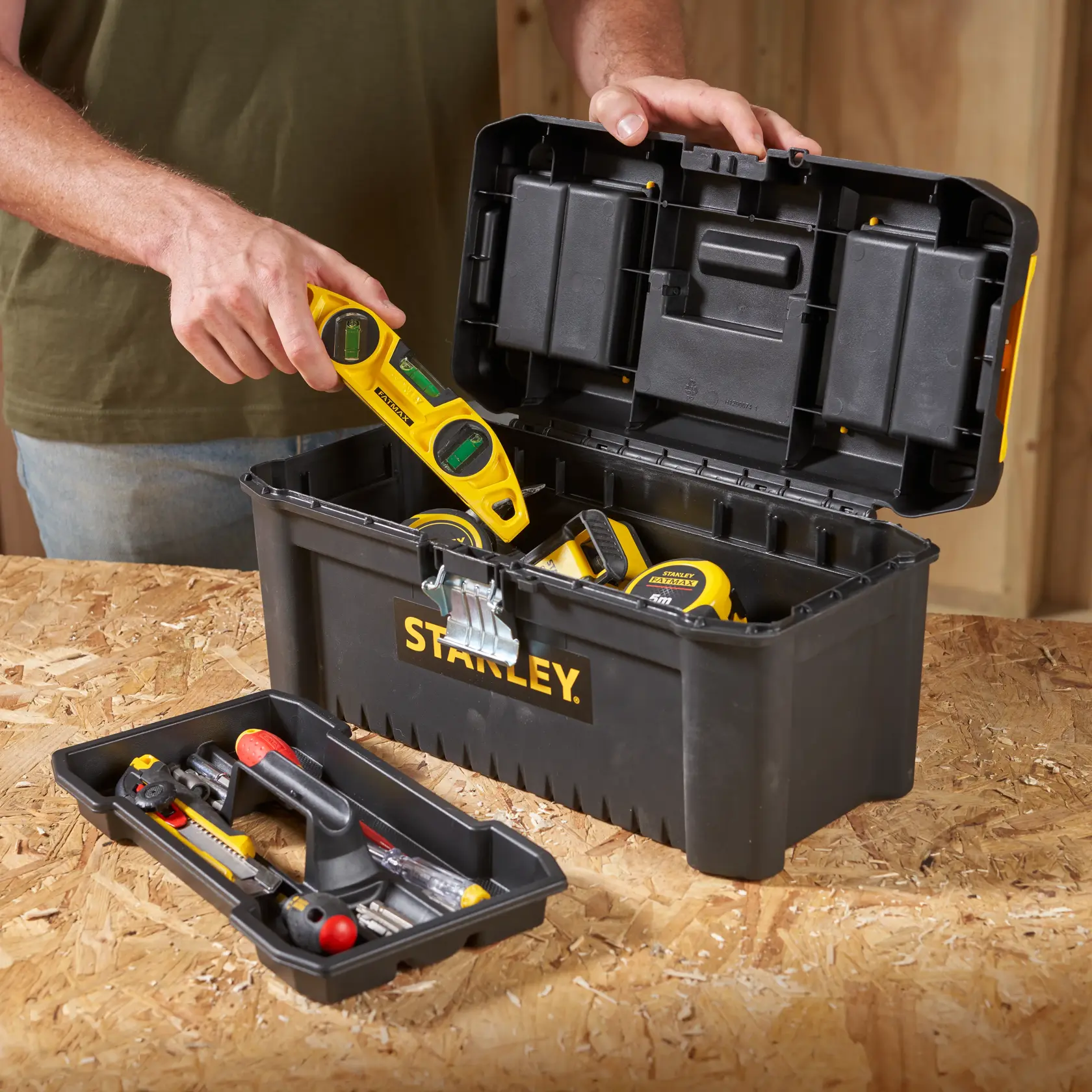 STANLEY STST1-75518-KR schwarze Werkzeugbox mit Werkzeugen, geöffnetem Deckel, auf Werkbank fotografiert.