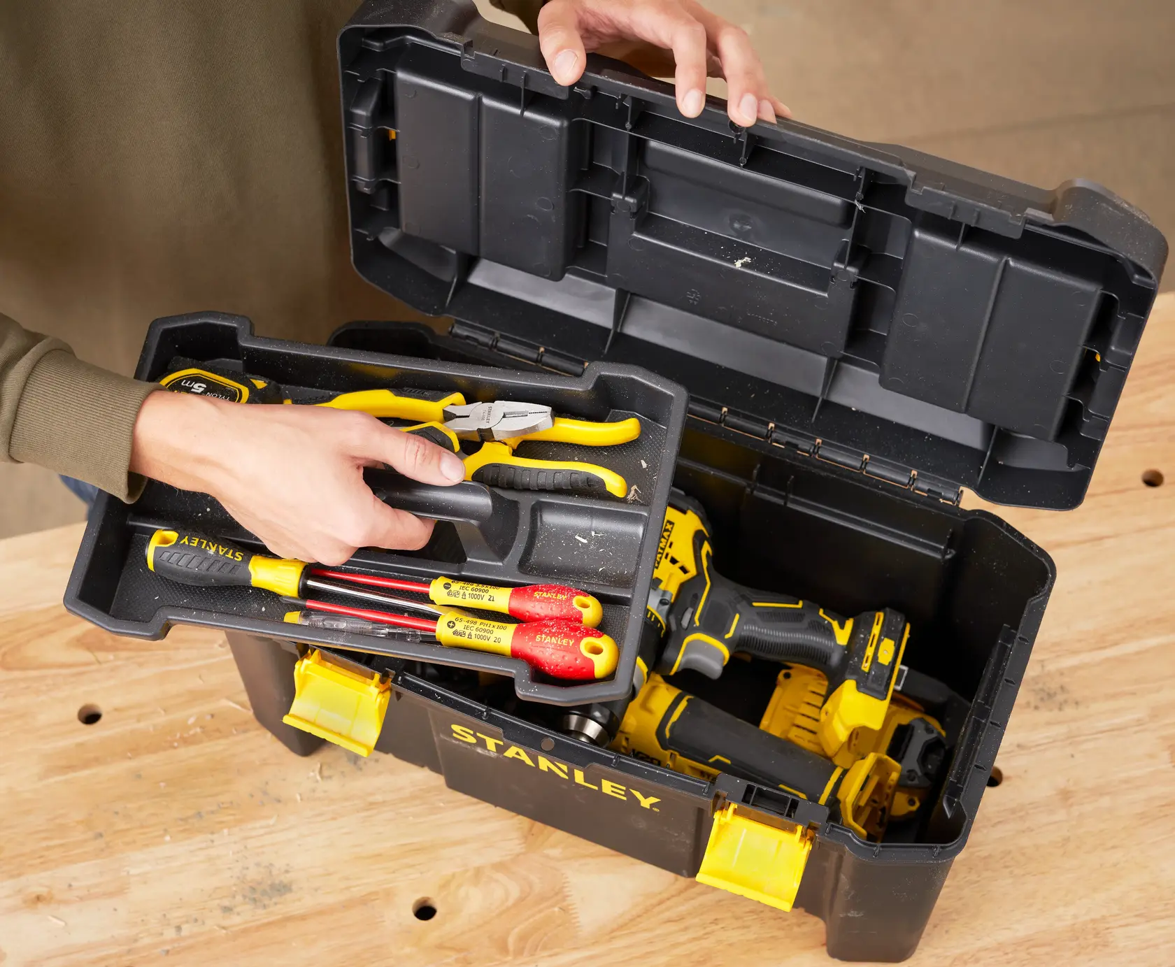 STANLEY STST1-75520 toolbox with hand tools and drill on workbench, top view.