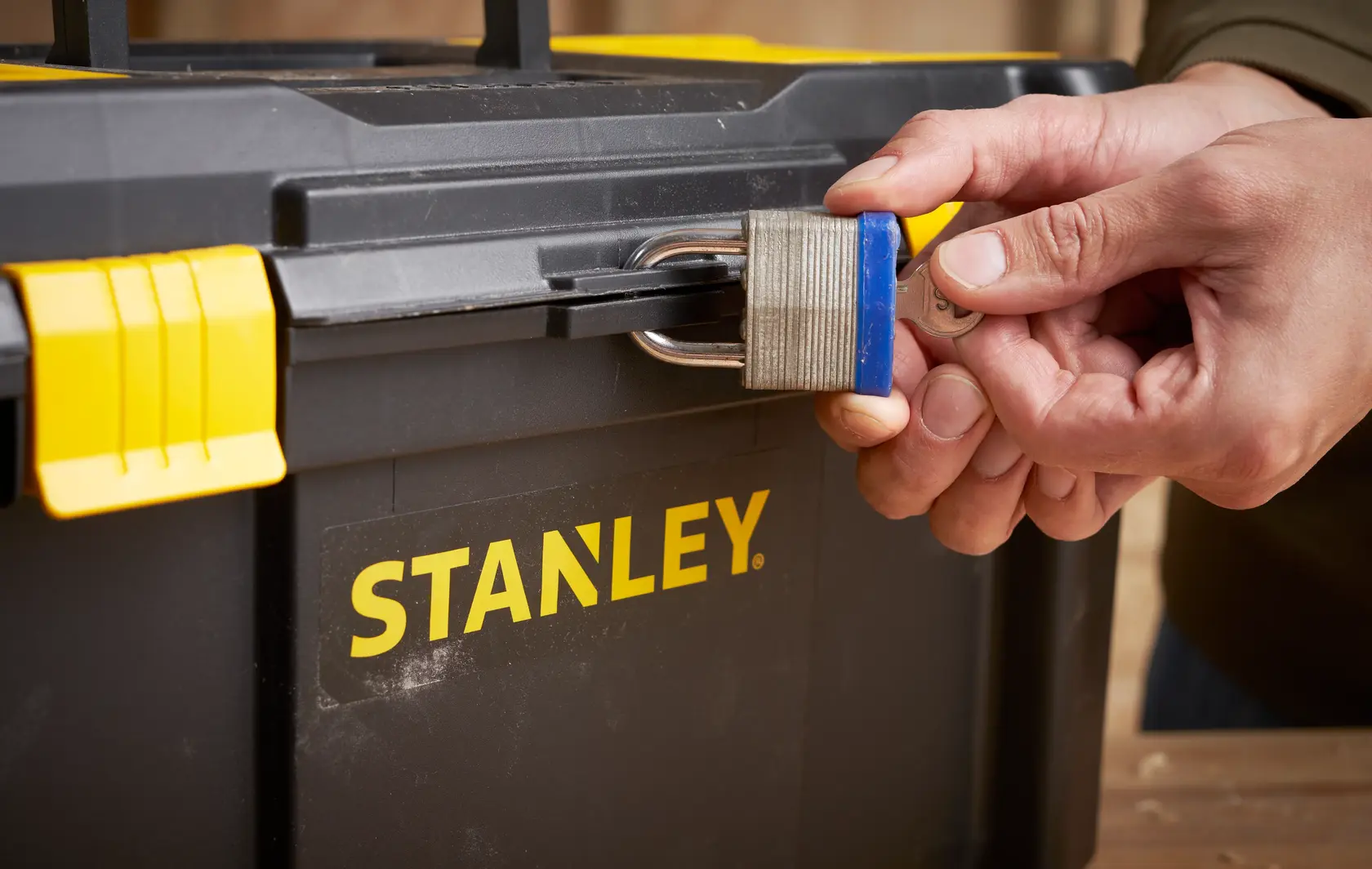 Photo of STANLEY STST1-75520 toolbox with yellow latch, secured by a padlock, close-up view.