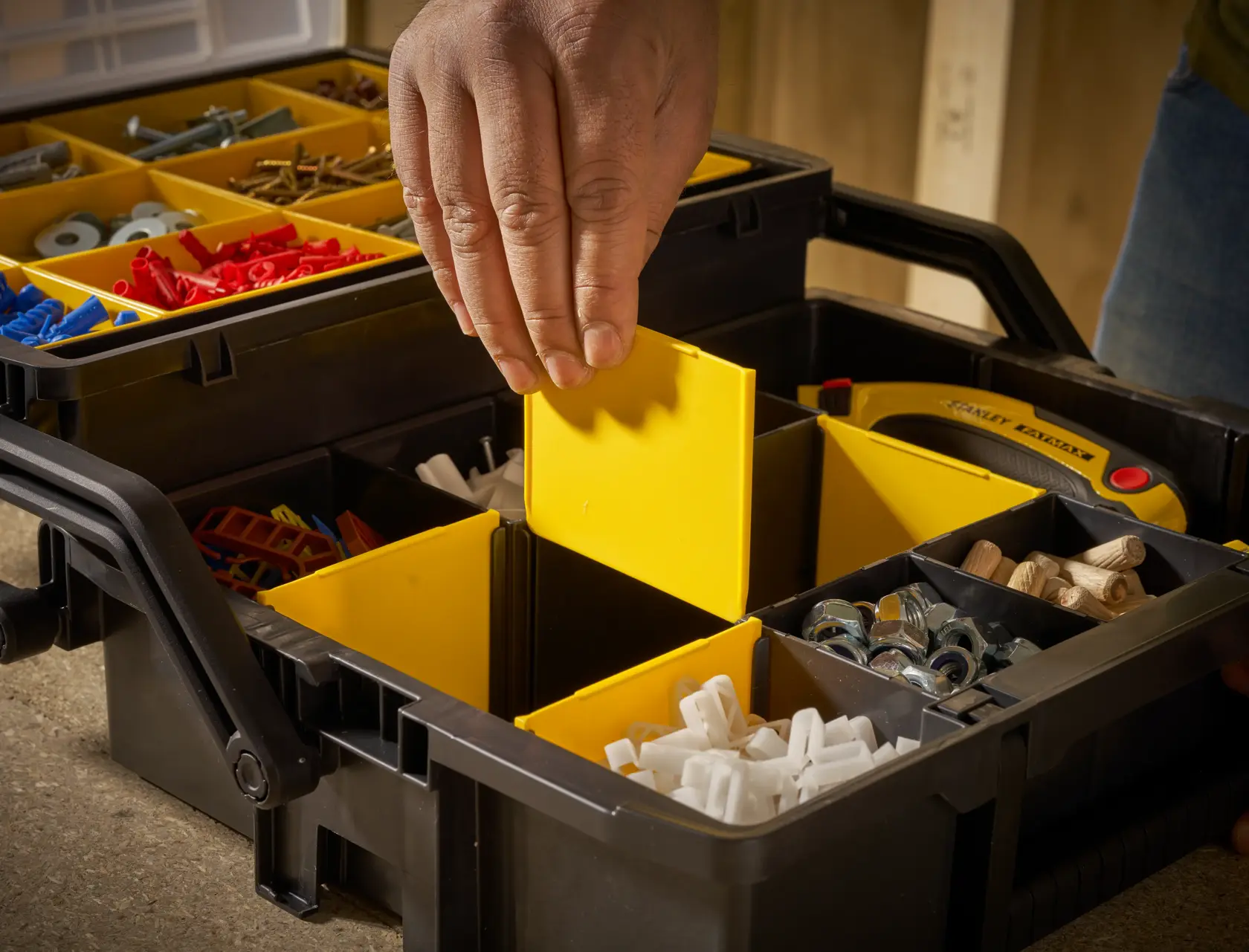 STANLEY STST1-75540 Organizerbox mit gelben Fächern, Hand stellt Trennwand, Nahaufnahme.