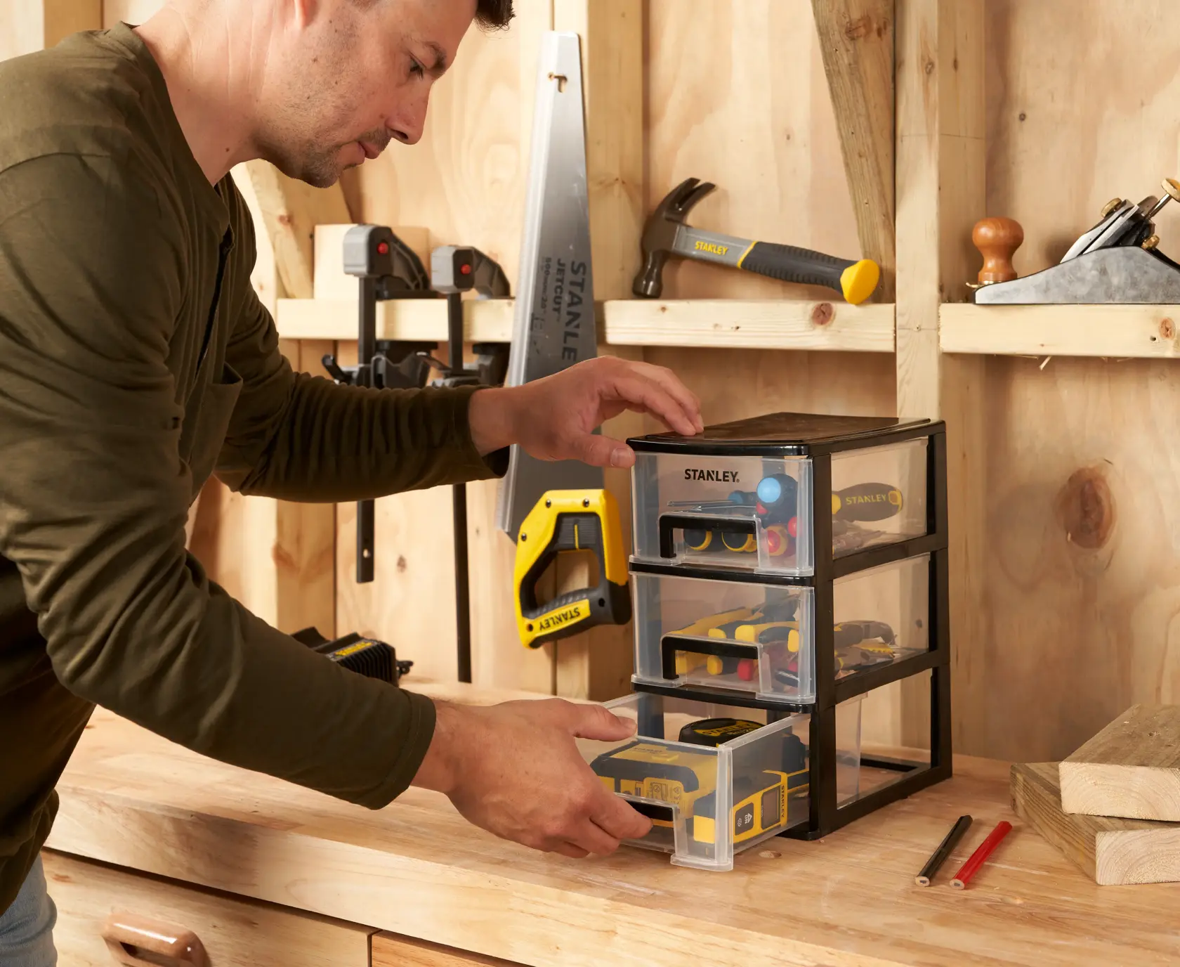 STANLEY STST40711-1 small parts organizer with three clear drawers on a workbench in a workshop.