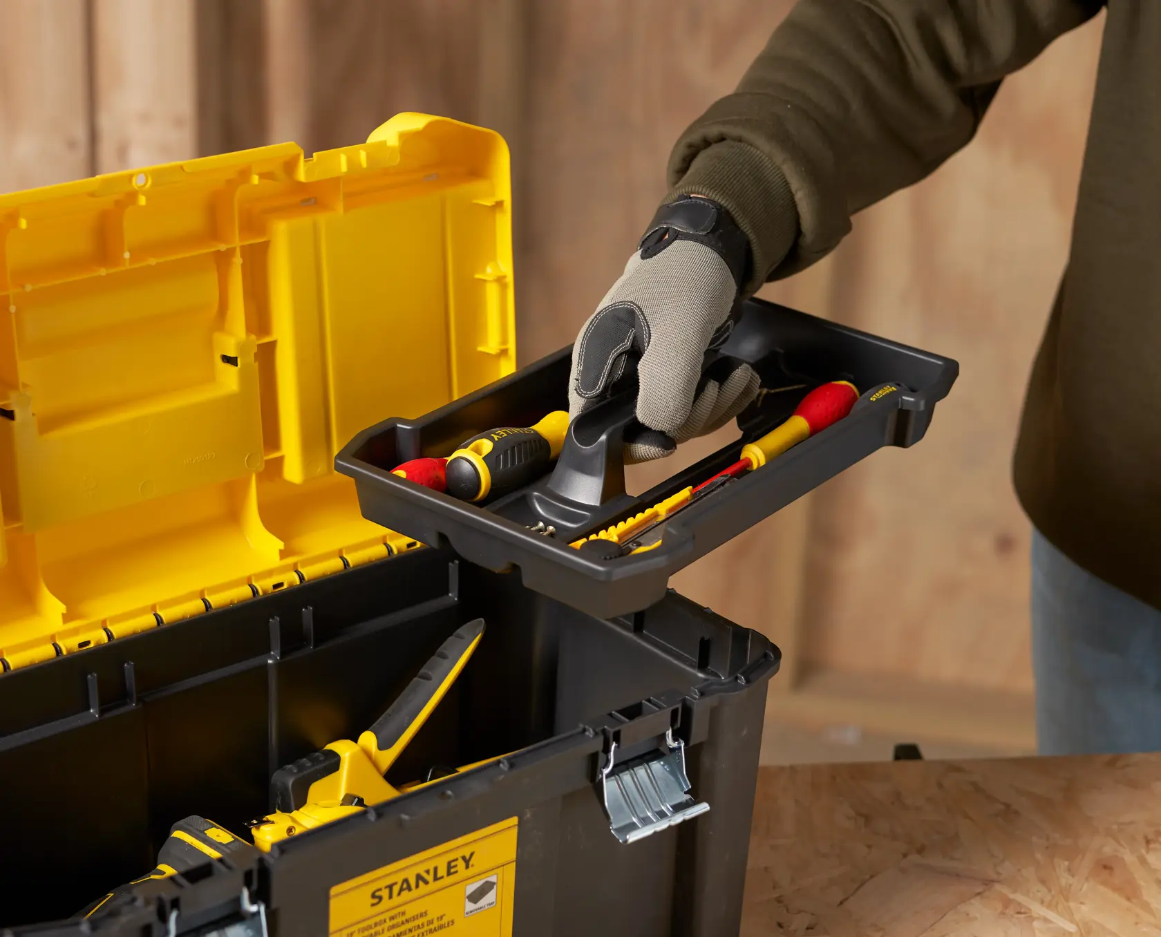 STANLEY STST75787-1 tool box with yellow lid, removable tray, hand holding tray with tools, side angle
