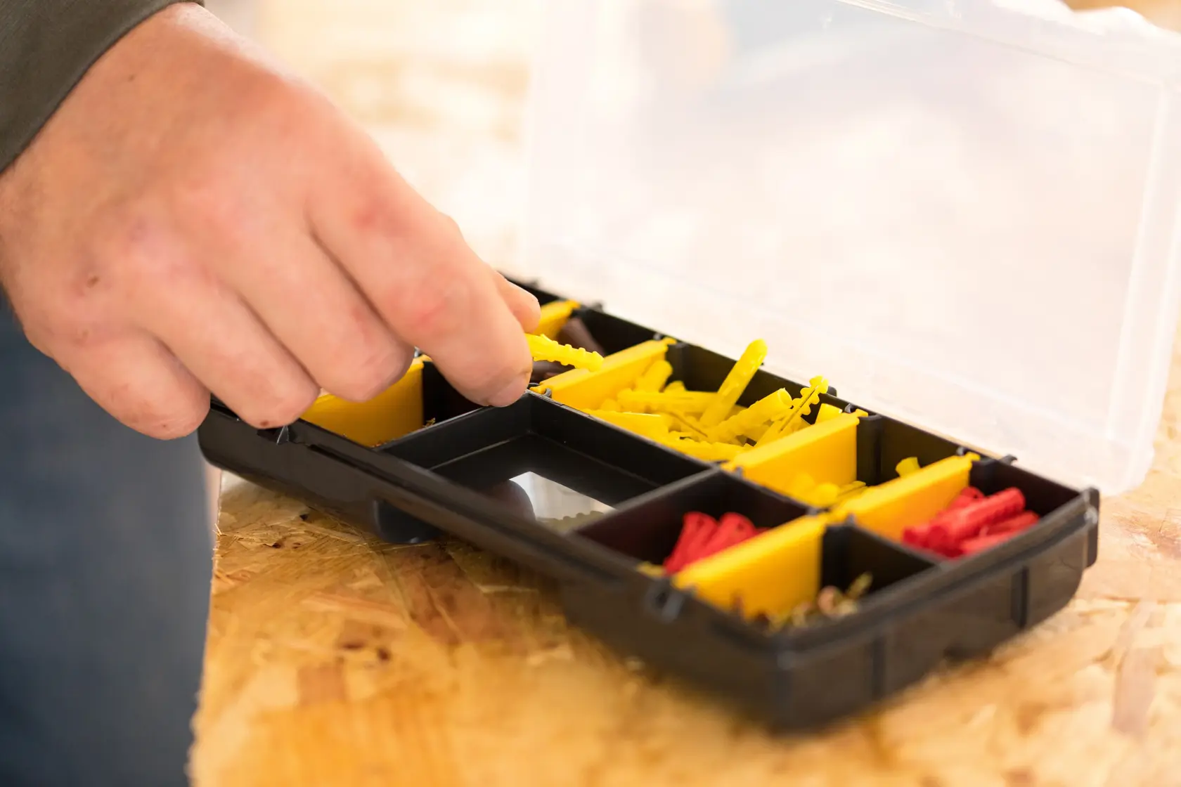 STANLEY STST81679-1 Organizer mit gelben und roten Fächern, Hand nimmt Gegenstand, Draufsicht.