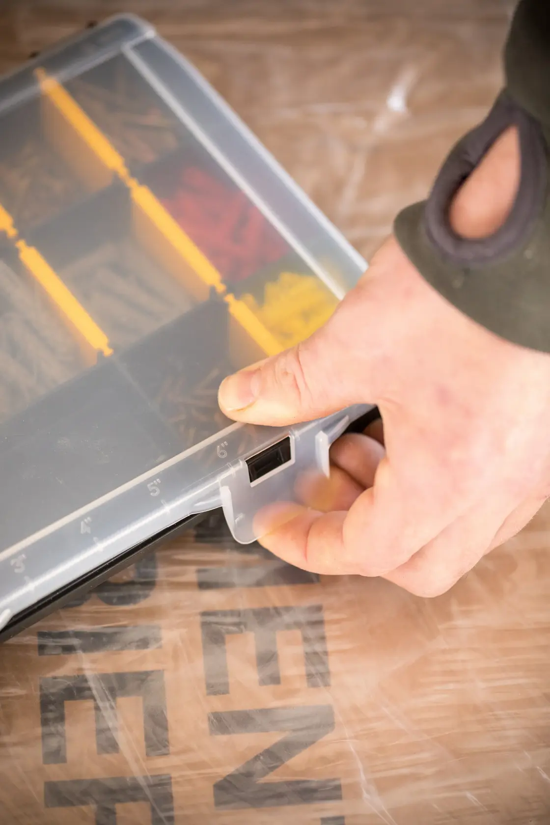 STANLEY STST81680-1 Kleinteile-Organizer mit durchsichtigem Deckel, gelben Trennwänden, Hand öffnet Verschluss, schräge Ansicht.