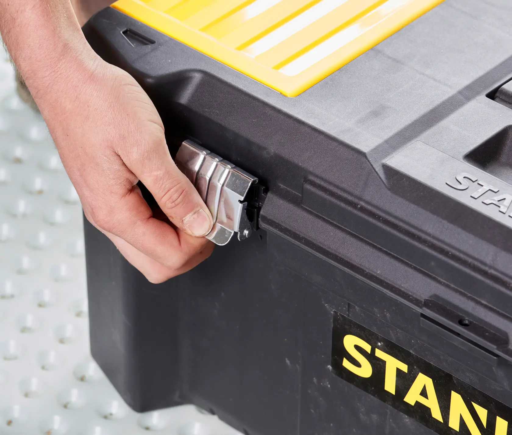 STANLEY STST82976-1 toolbox side view, hand opening metal latch, black body, yellow lid.