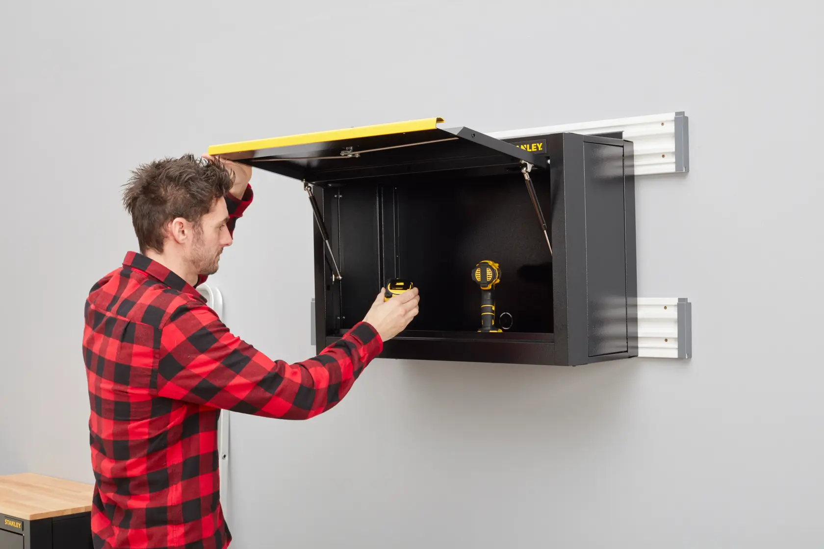 STANLEY STST97599-1 wall-mounted black storage cabinet with yellow lid in use, photography side angle.