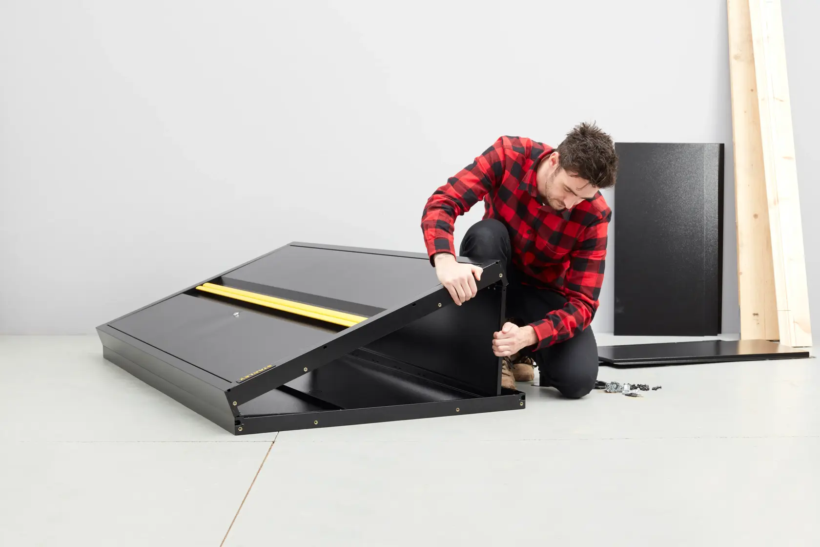 STANLEY STST97957-1 black metal cabinet assembly, side angle, with parts and person attaching panel.