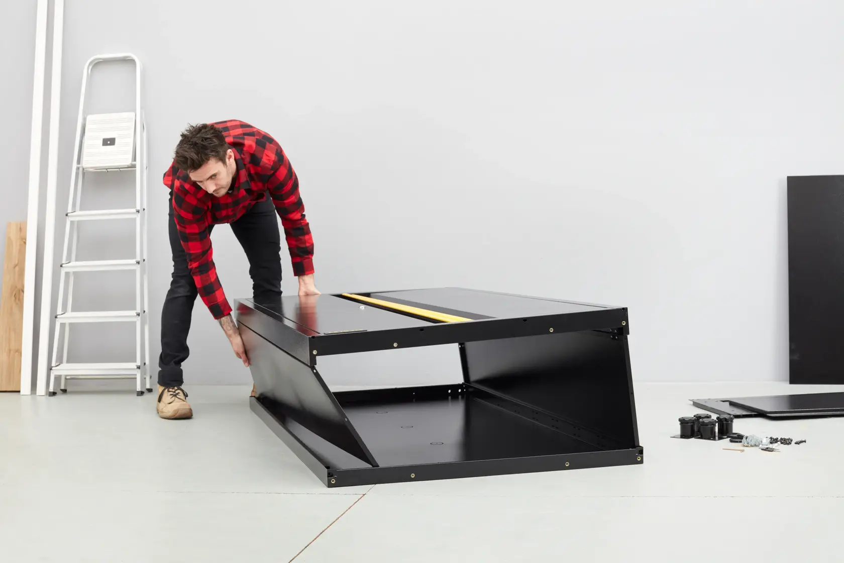 STANLEY STST97957-1 black cabinet being assembled, photo shows parts and tools on floor in workshop.