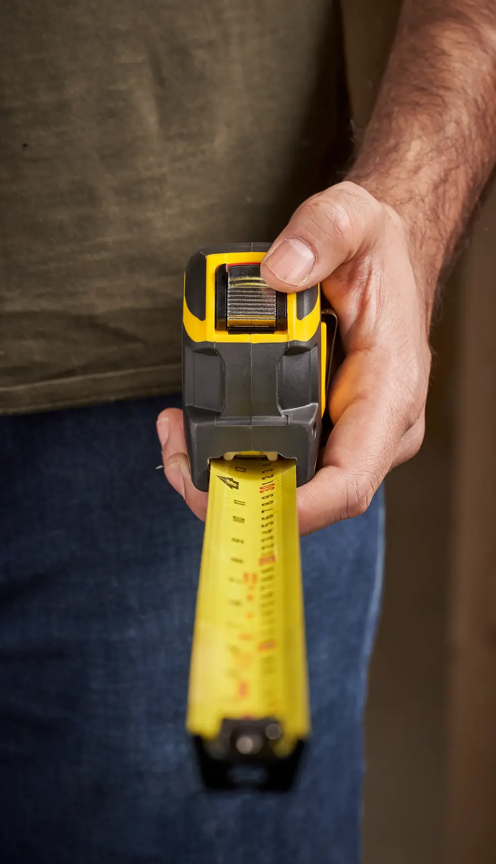 STANLEY XTHT0-33504 tape measure held by hand, close-up showing yellow blade and black grip.